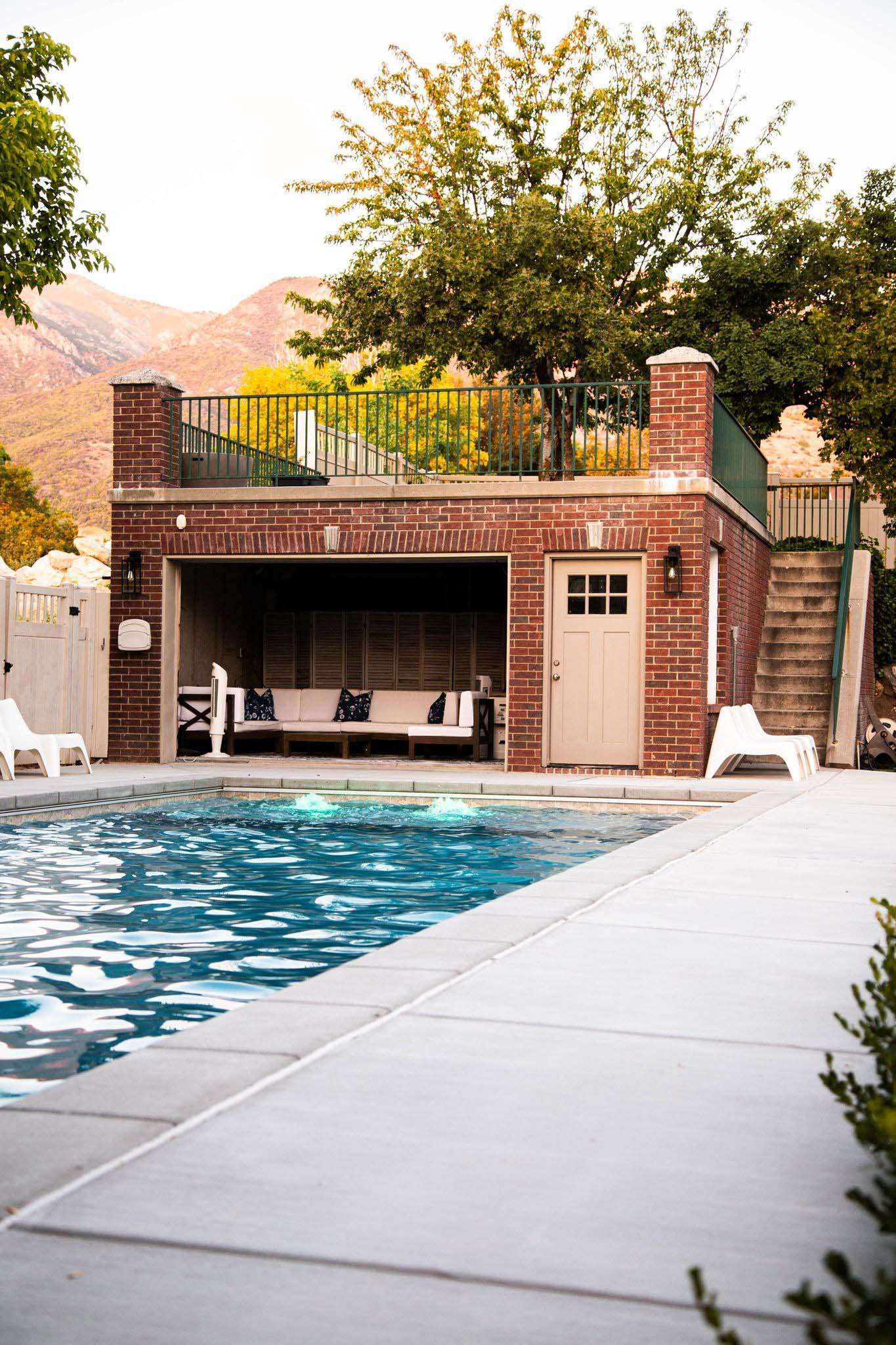 Backyard pool with brick pool house and mountain view.