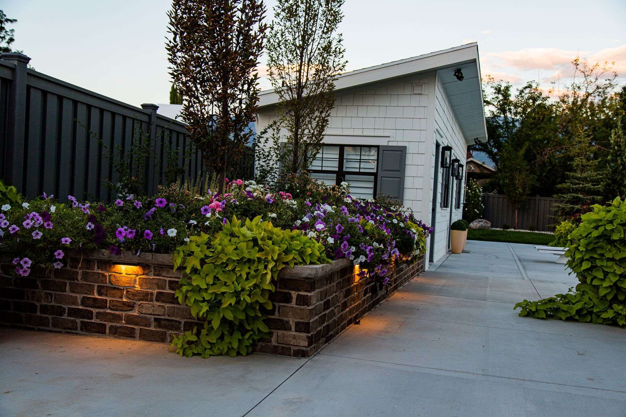 Suburban home exterior with flowering garden at dusk.