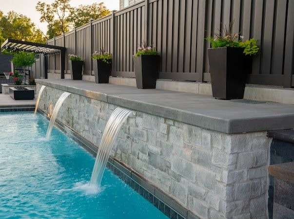 Modern backyard pool with water features and planters.