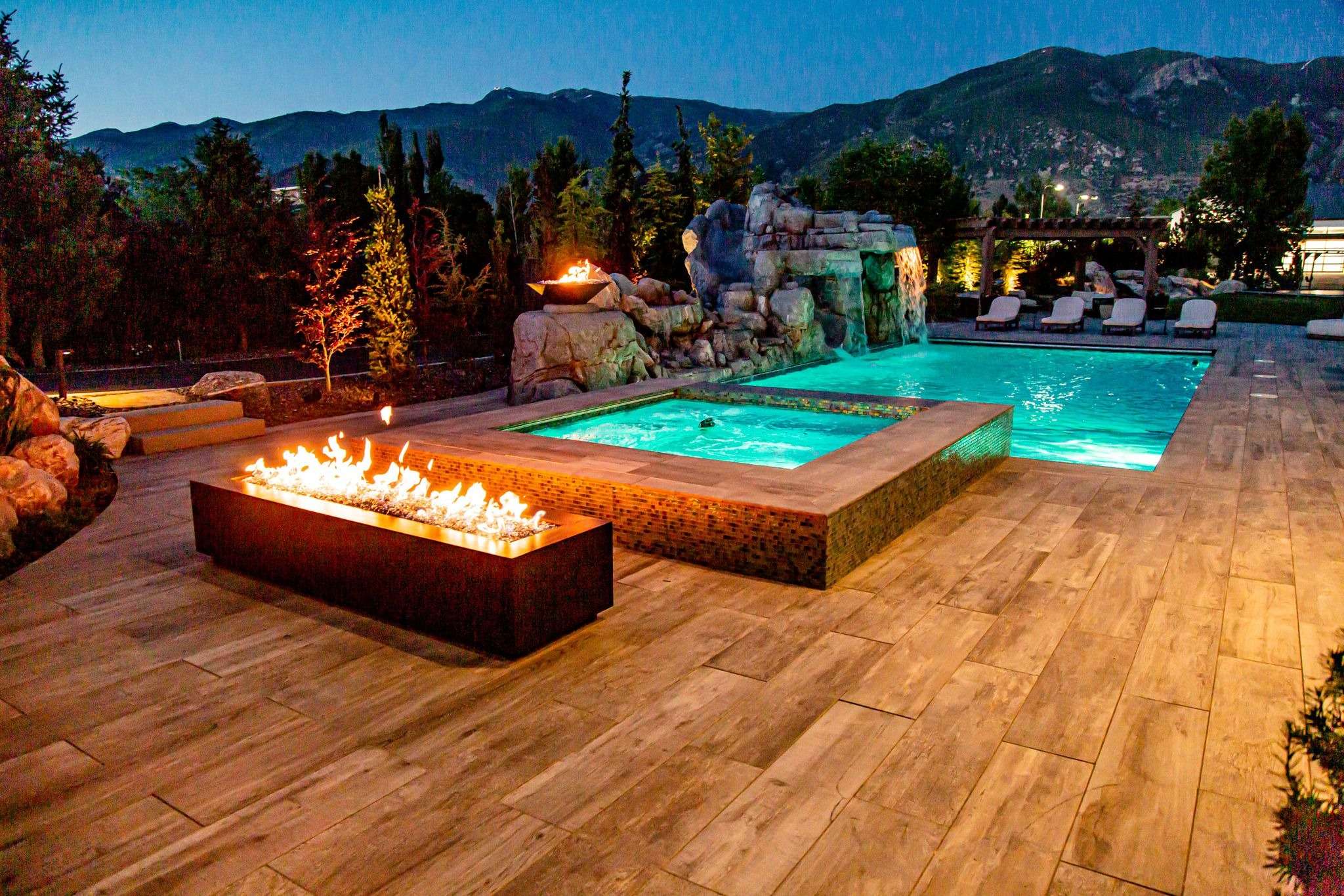 Luxurious backyard pool with fire pit at twilight.