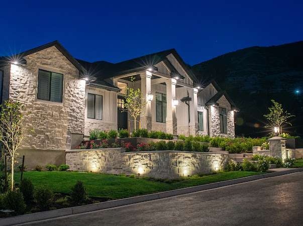 Illuminated modern house at night with landscaping.